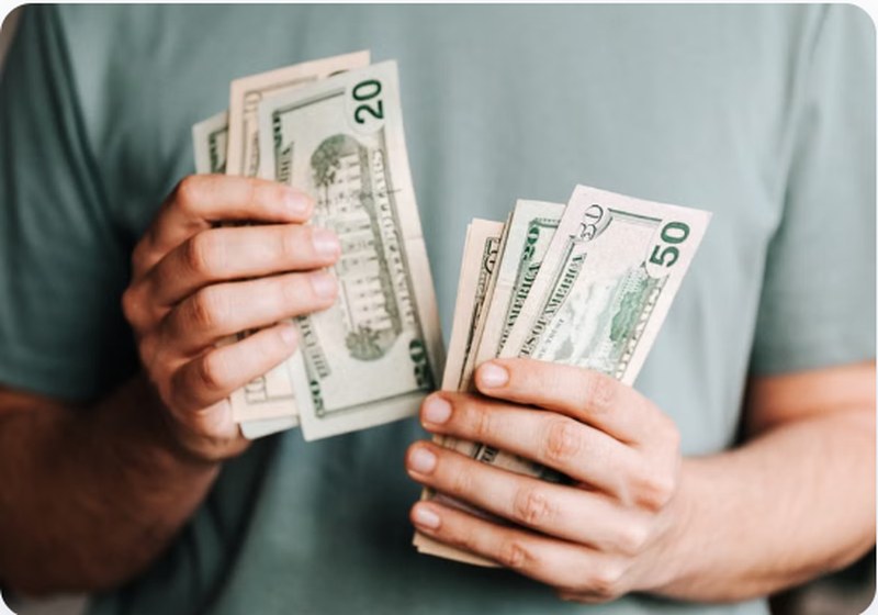 Person counting US dollar bills — Varo Bank fee-free checking account